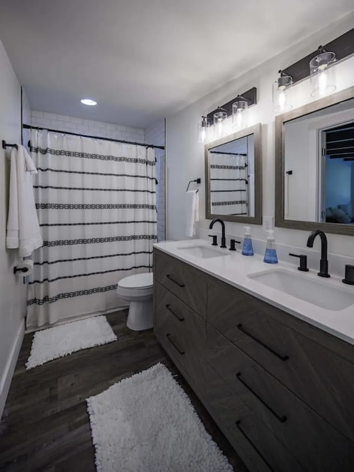 A modern bathroom featuring a double vanity, large mirrors, and a shower curtain, set in a tranquil, spa-like environment. The space is bright and inviting, hinting at both functionality and relaxation.
